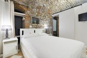 a bedroom with a white bed and a stone wall at BERGAMO art in Bergamo