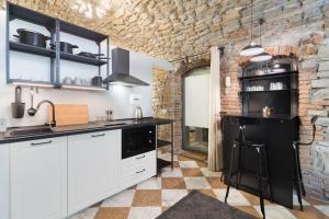 a kitchen with white cabinets and a stone wall at BERGAMO art in Bergamo