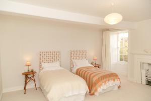 two beds in a white bedroom with a fireplace at Noyadd Trefawr in Cardigan
