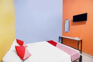 Un dormitorio con una cama con almohadas rojas. en SPOT ON 91887 Penginapan Rindu en Nagoya