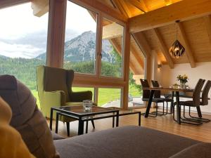 ein Wohnzimmer mit einem Tisch und Stühlen sowie einem großen Fenster in der Unterkunft 'dasBergblick' in Altaussee