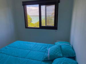 um quarto com uma cama azul e uma janela em Apto no centro de Tibau com vista para lagoa/mar em Pipa