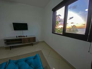 uma sala de estar com televisão e uma grande janela em Apto no centro de Tibau com vista para lagoa/mar em Pipa
