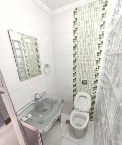 a bathroom with a sink and a toilet and a mirror at Lar de férias in São Vicente