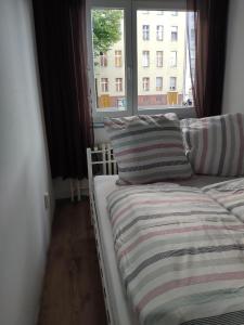 a bed with a striped blanket and a window at Apartment Berlin Mitte in Berlin