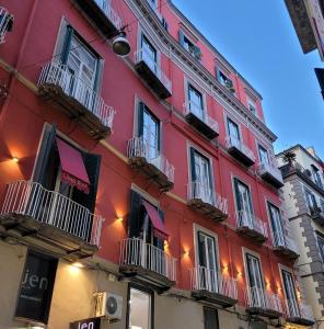 um edifício vermelho com varandas ao lado em Chiaja Hotel de Charme em Nápoles