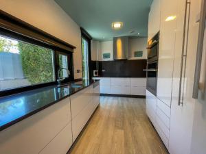 a kitchen with white cabinets and a large window at Lujosa villa vistas al mar y piscina climatiza in Sanxenxo