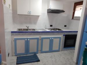 a kitchen with blue and white cabinets and a sink at Cià Evelina in SantʼAntìoco