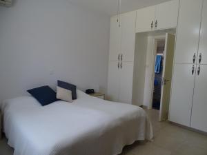 LE CAROUBIER splendid 3 bedrooms bungalow في Zanaja: غرفة نوم بسرير ابيض و دواليب بيضاء
