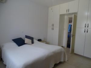 a bedroom with a white bed and white cabinets at LE CAROUBIER splendid 3 bedrooms bungalow in Zanaja +22 photos