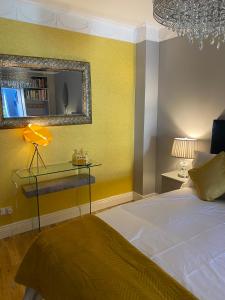 Dormitorio amarillo con cama y espejo en Beechtree House en Dublín