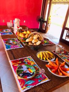 uma mesa com pratos de comida e frutas em Hostel Terra do Sol em Porto Seguro