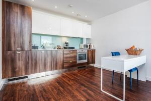 una cocina con armarios de madera y una mesa blanca en 2-Bed Apartment Near Basildon Train Station, en Basildon