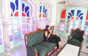 a woman sitting on a couch in a room at KothiPushkar in Pushkar