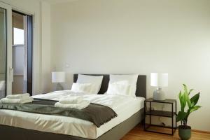 1 dormitorio con 1 cama grande con sábanas y almohadas blancas en Oberlaa New Apartment - 15 Min to City, en Viena