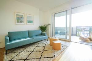 sala de estar con sofá azul y ventana grande en Oberlaa New Apartment - 15 Min to City, en Viena