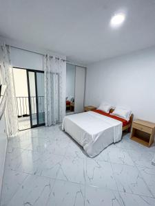 a white bedroom with a bed and a large window at Figo Apartamentos in Praia