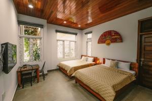 a bedroom with two beds and two windows at Le Robinet Villa - a journey into Hue citadel soul in Hue