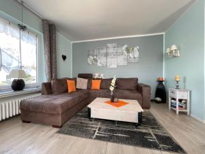 a living room with a brown couch and a coffee table at Ferienhaus SweetHome - eingezäunter Garten - 3 Hunde willkommen - ruhige Sackgasse in Bad Sachsa