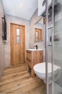 baño con puerta de madera, lavabo y aseo en Apartament Mikołowska en Gliwice