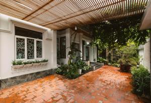 un porche de una casa con pérgola de madera en Le Robinet Villa - a journey into Hue citadel soul, en Hue