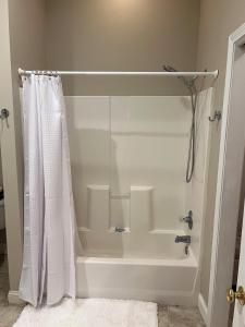 a bathroom with a shower with a white shower curtain at Stay at Rivermist Dahlonega in Dahlonega