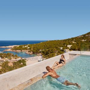 un hombre y una mujer sentados en el borde de una piscina en TRS Ibiza Hotel -All Inclusive Adults Only en San Antonio