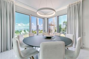 een eetkamer met een tafel, stoelen en ramen bij White Pearl Premium Villa Corfu in Evropoúloi