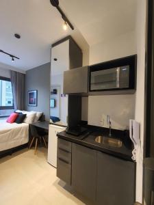cocina con fregadero y dormitorio con cama en Studio Allianz Perdizes en São Paulo