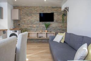 uma sala de estar com um sofá e uma televisão numa parede de tijolos em Bel appartement lumineux proche du centre-ville em Douai
