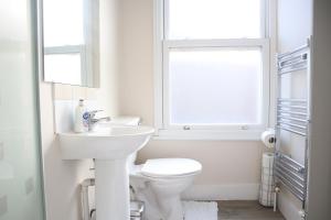 a white bathroom with a toilet and a sink at Twelve Thirty Serviced Apartments - 1 Croydon in South Norwood