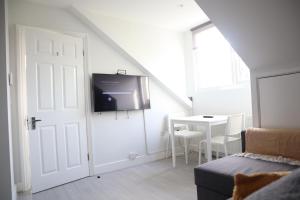 a room with a door and a table with a tv at Twelve Thirty Serviced Apartments - 1 Croydon in South Norwood