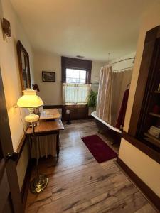 Habitación con cama, mesa y lámpara. en Upstairs Historic 1 Bedroom 1 Bath Suite with Mini-Kitchen, Porch & River Views, en Elkins