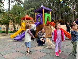 um grupo de crianças e um cão num parque infantil em Hotel Surami em Surami