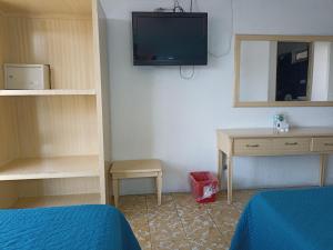 a room with a bed and a desk and a tv at Hotel Viena in Irapuato