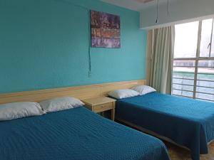 2 camas en una habitación con paredes azules y ventana en Hotel Viena, en Irapuato