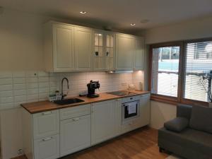 a kitchen with white cabinets and a sink and a couch at Vytauto 423 Apartments by JK in Palanga