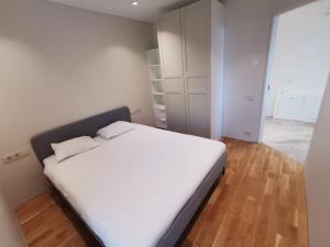 a bedroom with a large white bed and wooden floors at Vytauto 423 Apartments by JK in Palanga +3 photos