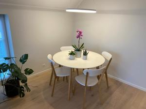 una mesa de comedor con sillas blancas y flores púrpuras en Modern Central Apartment HOTEL, en Keila