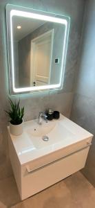 a bathroom with a white sink with a mirror at Modern Central Apartment HOTEL in Keila