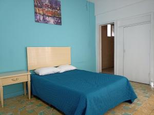 Dormitorio azul con cama y mesa de madera en Hotel San Carlos, en Irapuato