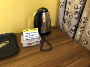 John's Highland Comfort (Guest House) في ماجوردا: طاولة مع وعاء القهوة وكتاب عليها