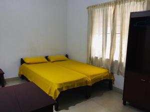 a yellow bed in a room with a window at Hebron Inn in Cochin