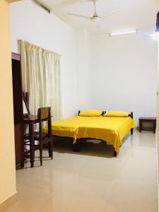 una camera con un letto giallo con una coperta gialla di Hebron Inn a Cochin