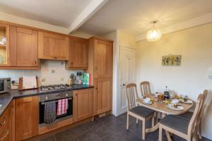 a kitchen with wooden cabinets and a table with chairs at Chapelton Cottage No 2 in Kirkcudbright