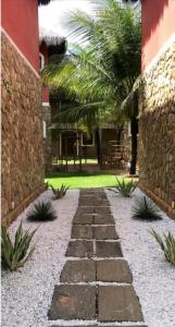 a stone pathway in front of a building with a palm tree at Canoappart in Canoa Quebrada