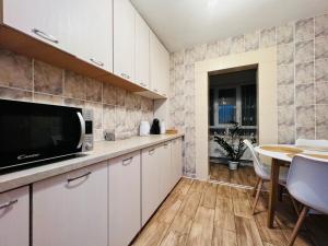 una cocina con armarios blancos y una mesa con sillas. en Altheda Living Tineretului E8 en Suceava