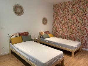 2 Betten in einem Zimmer mit einer Wand in der Unterkunft La maison du manoir 1900 une expérience en famille in La Ferté-Gaucher