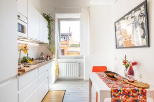 a kitchen with white cabinets and a table and a window at PIGNETO VILLAGE Roma Guest House Apartment in Rome