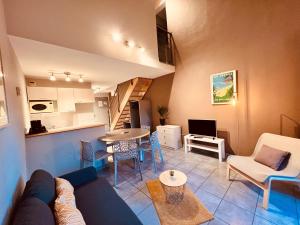 a living room with a couch and a table and a kitchen at The Originals Boutique, Hôtel Le Cap, Gap Sud in Tallard